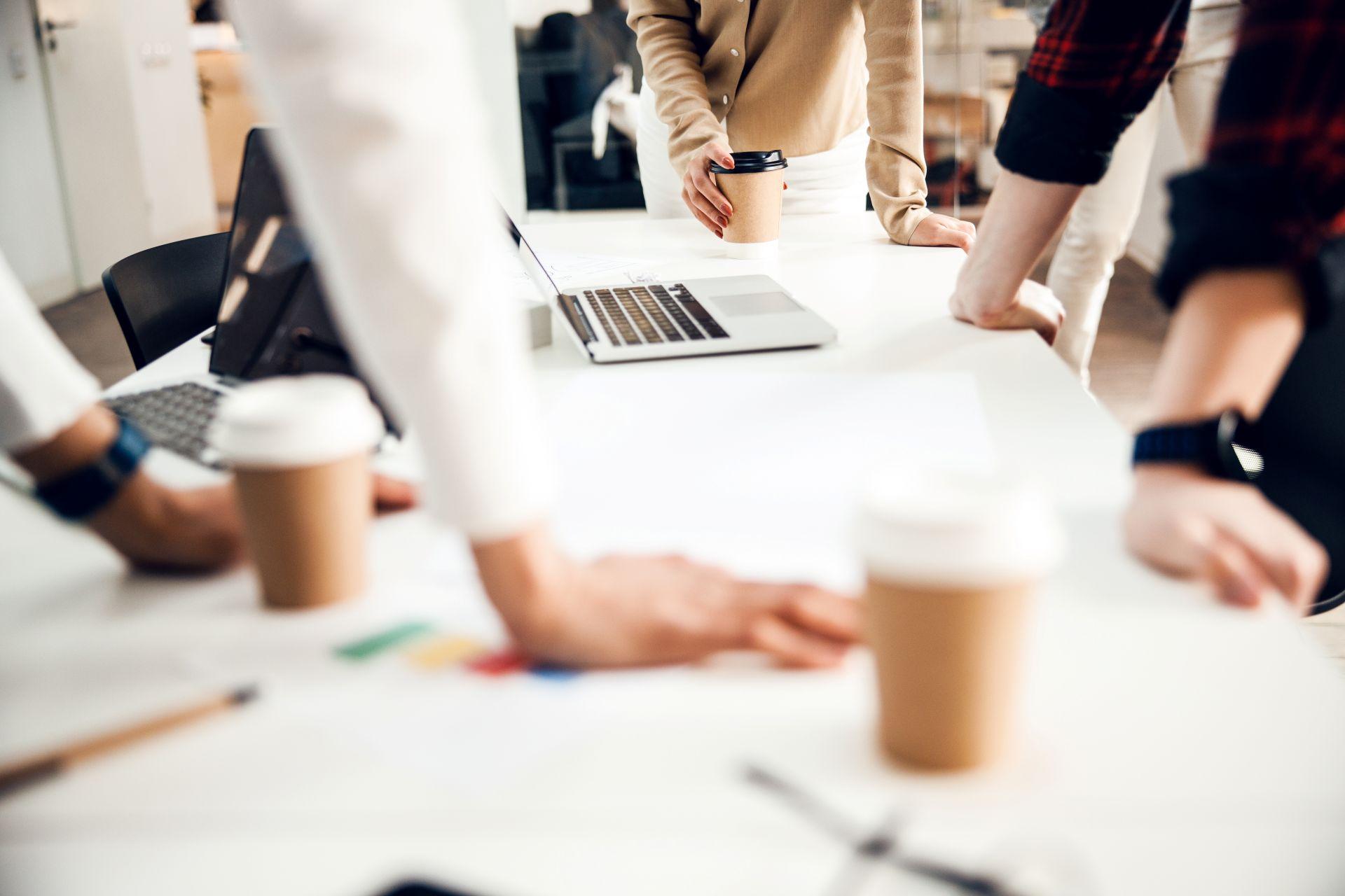 Close-up of team planning at a table with laptops and coffee – illustrating strategic collaboration provided by an onlyfans agency