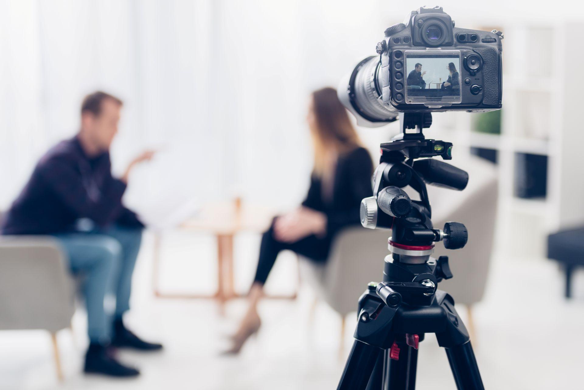 Camera filming an interview with blurred participants – representing anonymous creator insights into working with an onlyfans agency